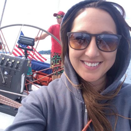 A selfie photograph of WebDevStudios Director of Project Management, Cristina Holt, while at a fair, wearing a hoodie shirt and sunglasses, and smiling at the camera.