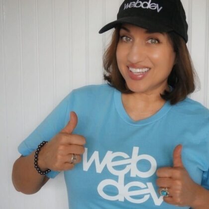 This is a photo of WebDevStudios Marketing Manager Laura Coronado. She is wearing a black baseball cap with the WebDevStudios logo and a blue T-shirt also with the logo. She is smiling and giving two thumbs up.