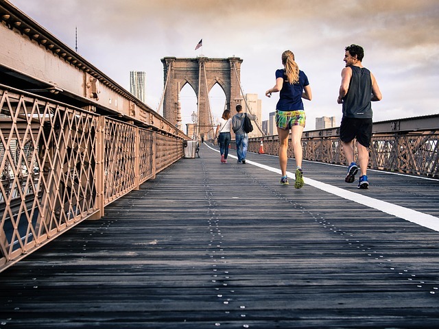 A photo image of two people with their backs to the camera as they jog on a bridge.