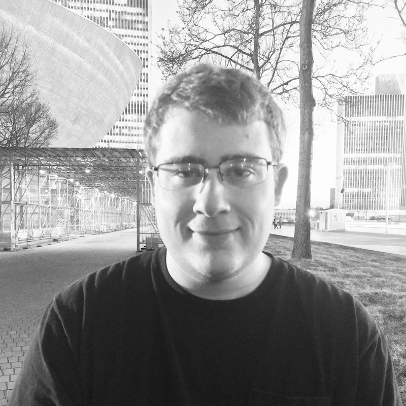 A black and white photograph of George Gecewicz, a Backend Engineer at WebDevStudios. He's wearing glasses and slightly smiling at the camera.