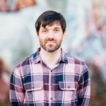 A photograph of WebDevStudios Backend Engineer Evan Hildreth, who is photographed from the chest up while wearing a plaid shirt and slightly smiling at the camera.