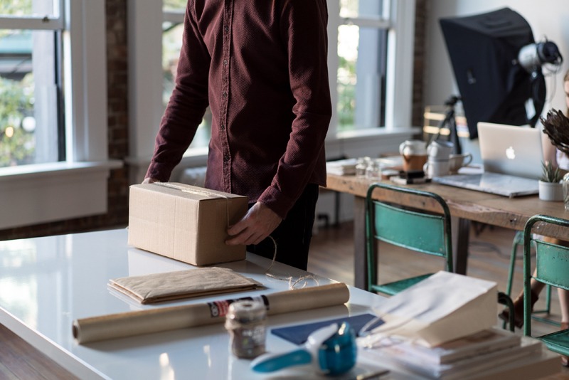 A photo image of a man packing a box with a product for shipment to an eCommerce customer.