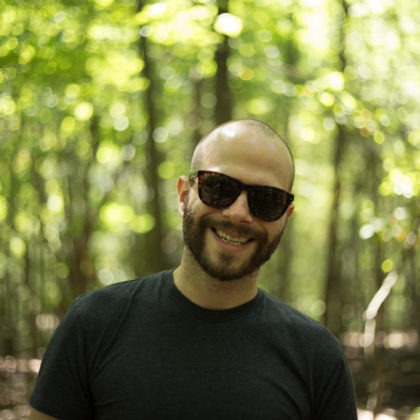 A portrait of David Romsey, Backend Engineer at WebDevStudios. David is outdoors wearing sunglasses and facing the camera and smiling.