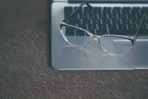 This is a photo of a pair of eyeglasses sitting on an open MacBook, near the touchpad.