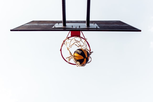This is an upward angle photo of a basketball falling through a basketball hoop.