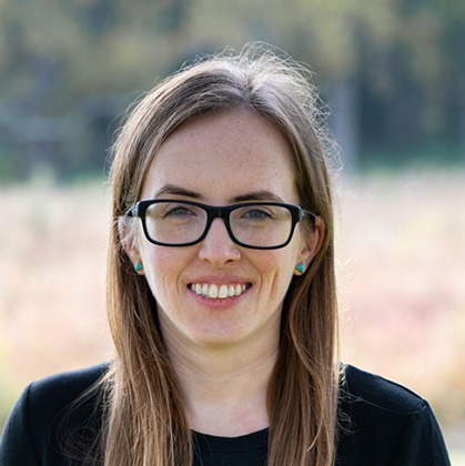 This is an outdoor portrait photo of Lauren Pittenger, Frontend Engineer at WebDevStudios. She is wearing glasses and smiling at the camera.