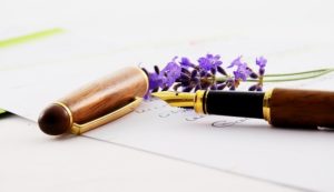 This is a close-up photograph of purple lavender flowers and a calligraphy pen with the cap off.