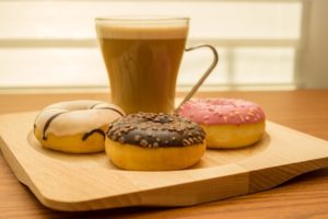 This is an image of a cup of coffee and three donuts.