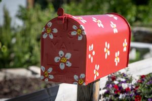 This is a photo of a red mailbox with white daisies painted on it.
