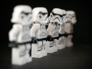 This is a close-up photo of five Lego Strom Troopers facing the same direction, but one of them is leaning a little forward and turned to look into the camera.