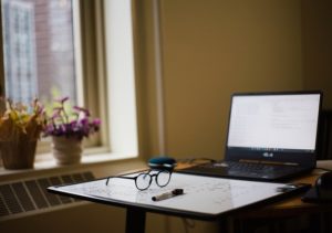 This is a photo of an in-home study room with an open laptop, a white board, and a pair of glasses.