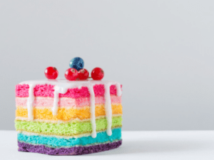 This is an image of a rainbow-layered cake with icing dripping on the sides.