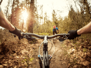 This is a bicycle rider point-of-view photo that shows the rider and photographer bicycling on an outdoor trail through the woods.